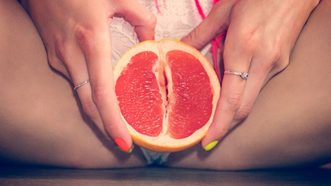 mulher segurando fruta na região genital